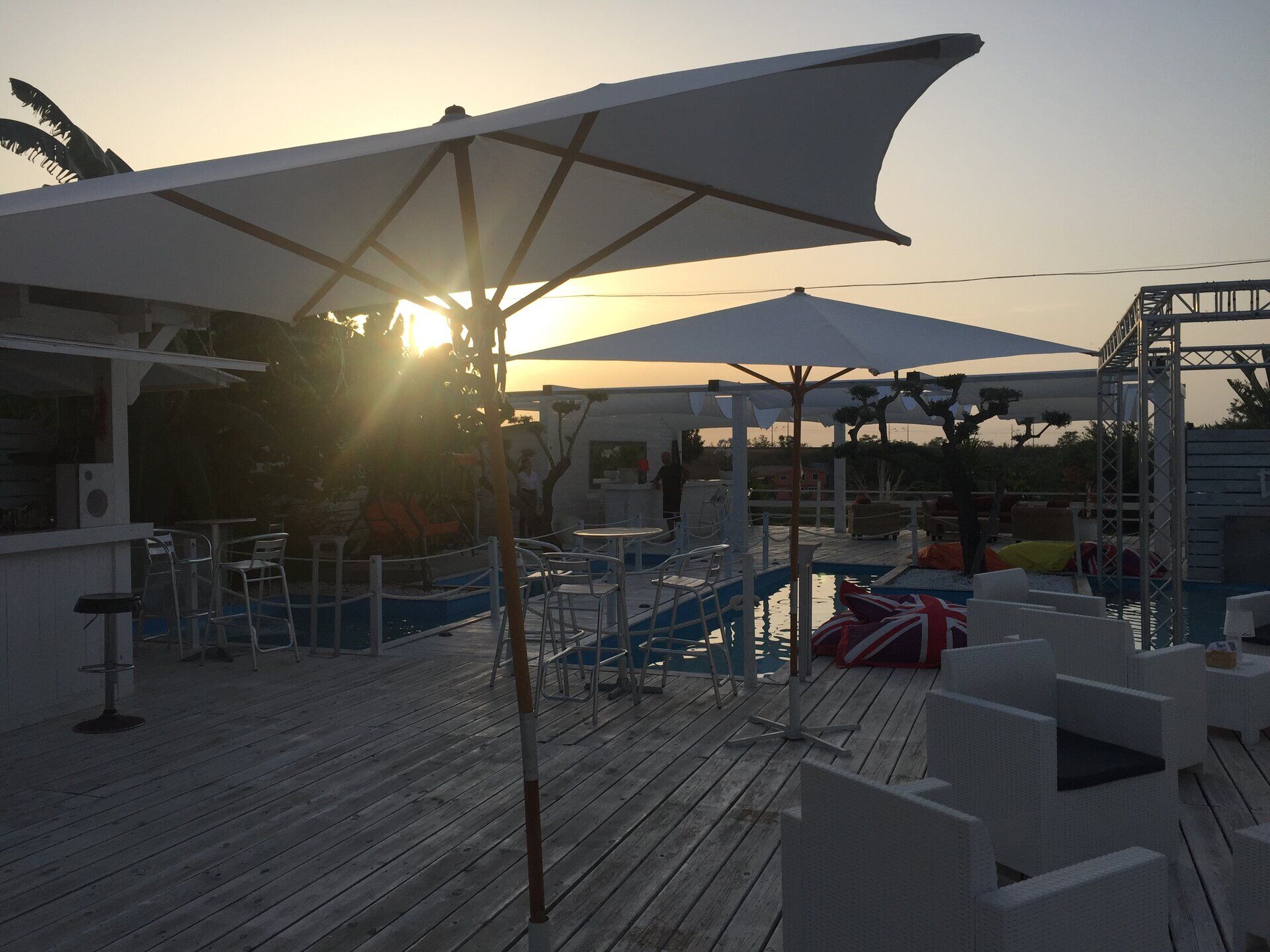 Deck esterno con ombrelloni e area d'acqua al tramonto